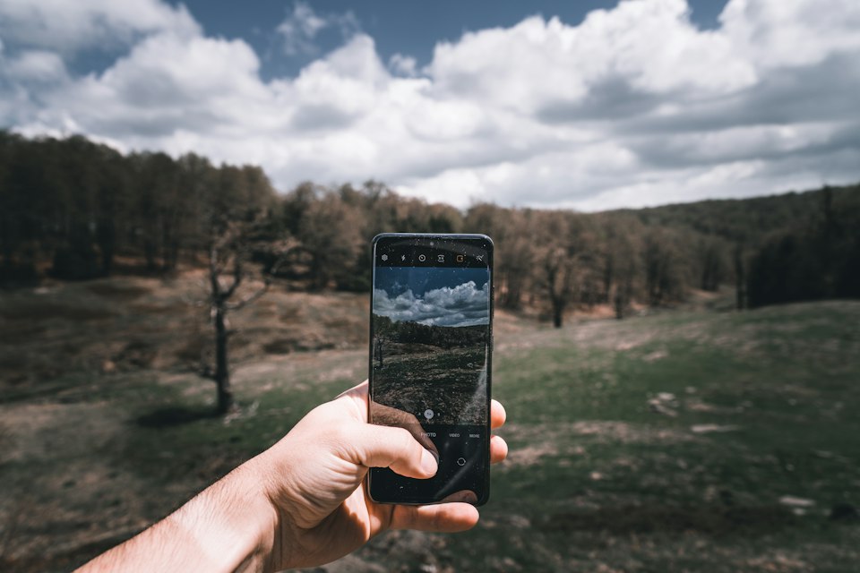 Person using a smartphone outdoors to take a photograph