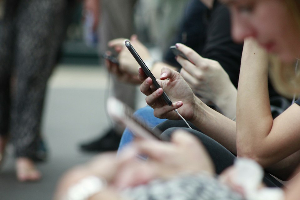 People using smartphones while waiting in a public place
